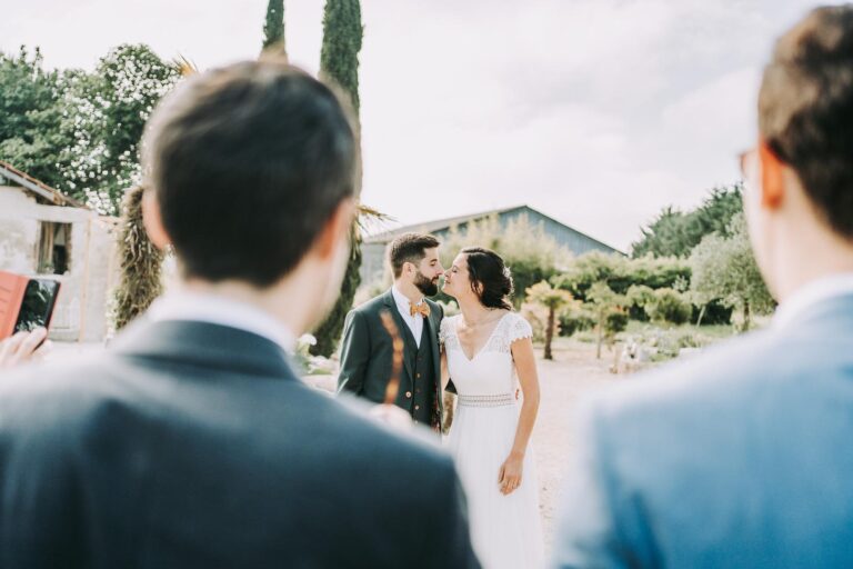 Des mariés s'embrassant devant un groupe de personnes, capturés par un photographe mariage Dax.