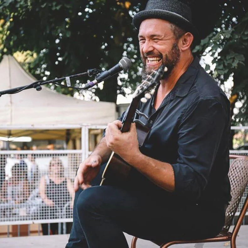 Un homme au chapeau jouant de la guitare acoustique, capturant l'essence du commentaire devenir photographe.