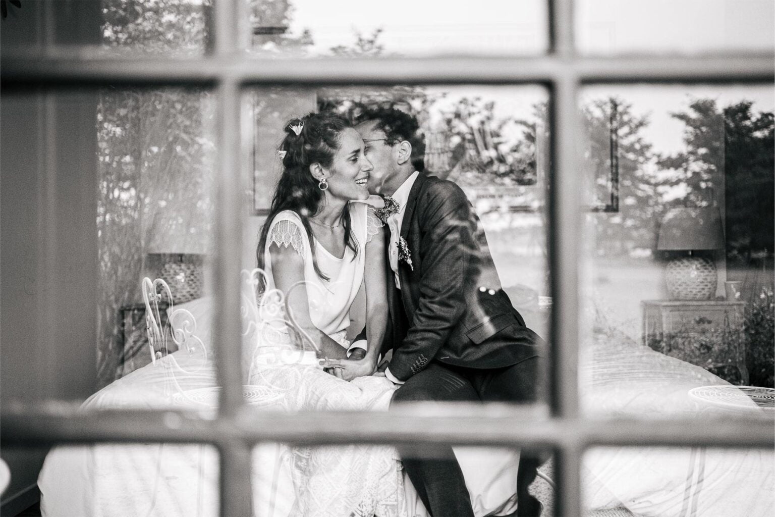 Des mariés assis sur un lit au mariage domaine bouhemy.