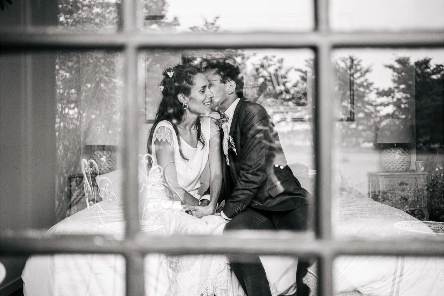 Des mariés assis sur un lit au mariage domaine bouhemy.