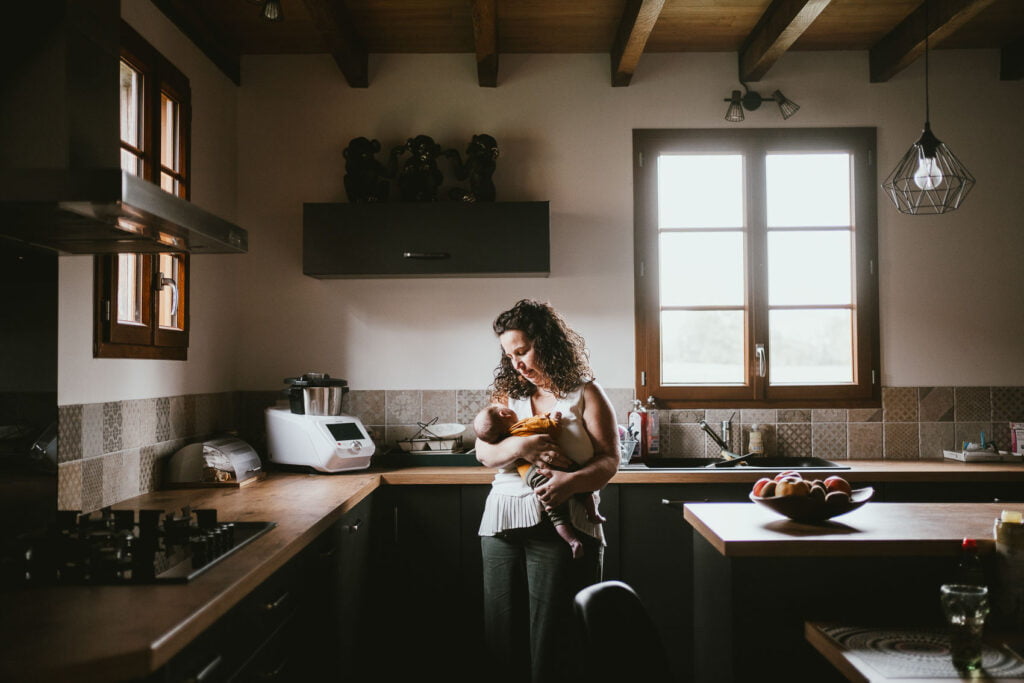 Une femme tenant un bébé dans une cuisine lors d'une séance photo débarque.