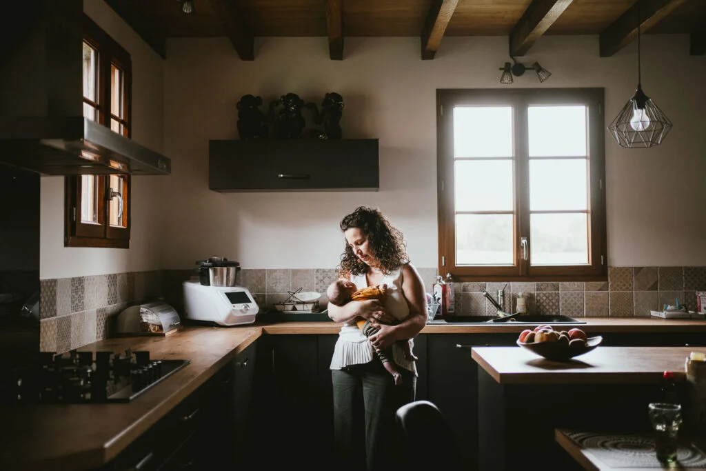 Une femme tenant un bébé dans une cuisine lors d'une séance photo débarque.