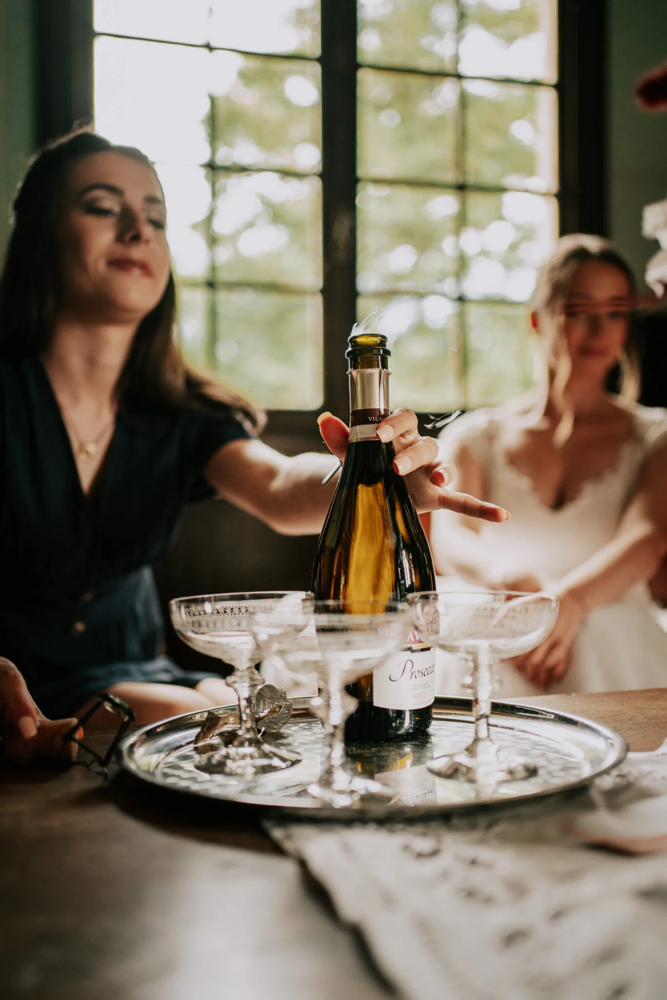 Une femme verse une bouteille de champagne dans un verre.