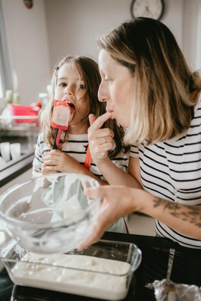Mère et fille préparant un gâteau dans la cuisine tout en prévoyant de faire des photos de vacances.