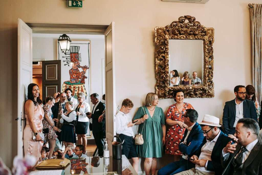 Un groupe de personnes debout autour d'un miroir dans une pièce, photographié lors d'un mariage à Biarritz.
