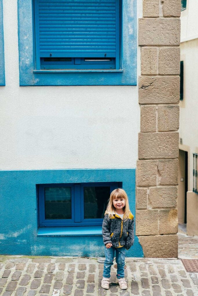 Une petite fille debout dans une rue pavée, prête à faire des photos de vacances.