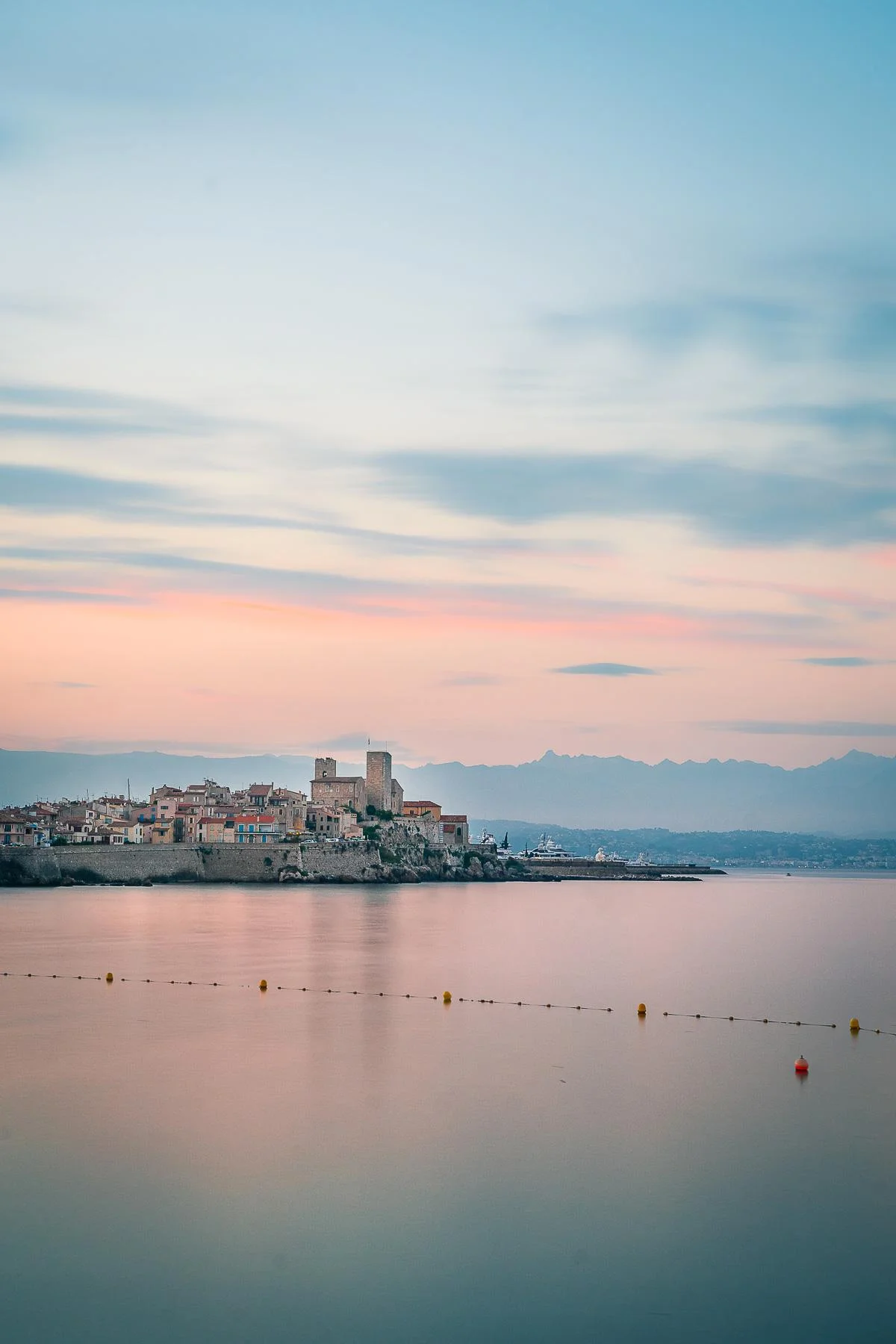 Une petite ville au bord de l'eau avec un château en arrière-plan, parfaite pour faire des photos de vacances.
