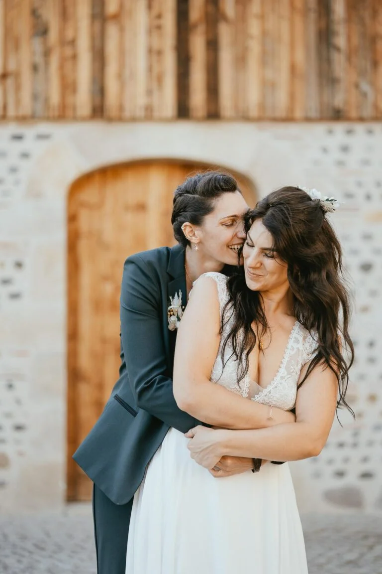 Des mariés s'embrassant devant une porte en bois après leur mariage.