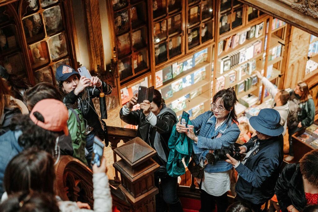Un groupe de personnes prenant des photos dans une librairie pendant leurs vacances à Porto.