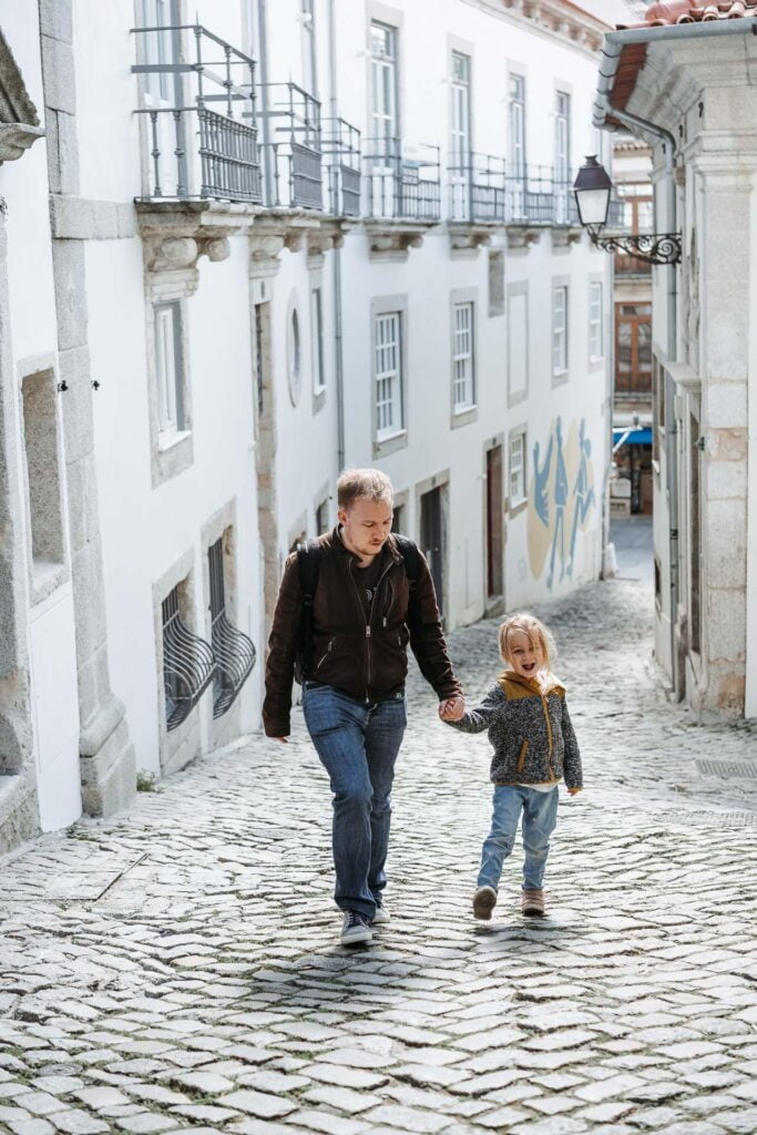Un homme et un enfant marchant dans une rue pavée pendant les vacances à Porto, au Portugal.