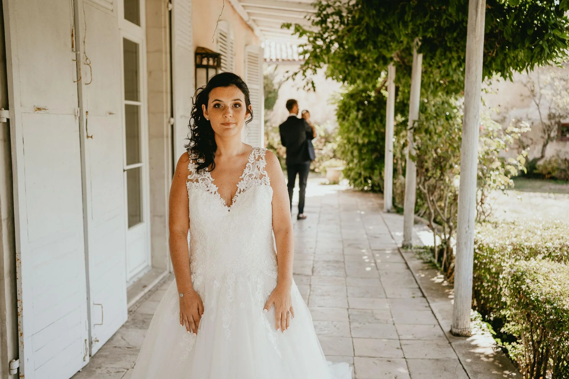 Une mariée en robe de mariée debout devant une maison pour sa cérémonie laïque.