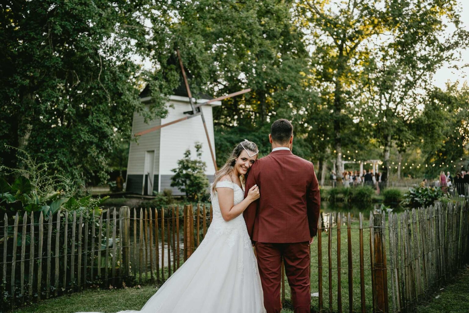 Des mariés debout devant un moulin à vent lors de leur mariage à Biscarrosse.
