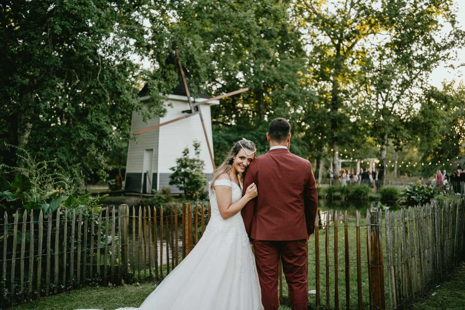 Des mariés debout devant un moulin à vent lors de leur mariage à Biscarrosse.
