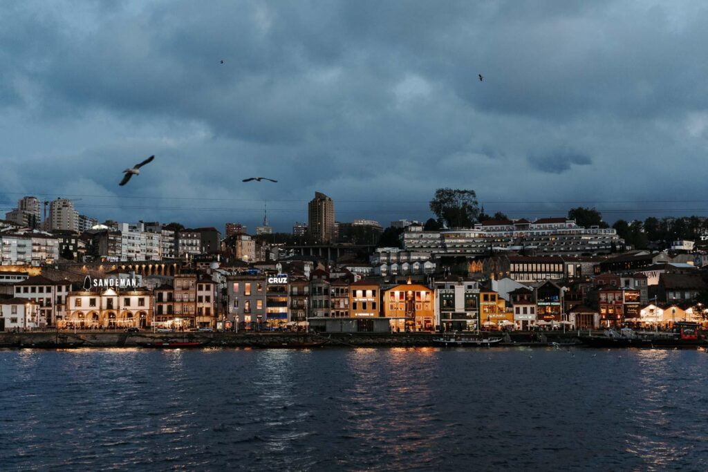 Ville portugaise au crépuscule avec des oiseaux volant au-dessus de l'eau pendant les vacances à Porto.