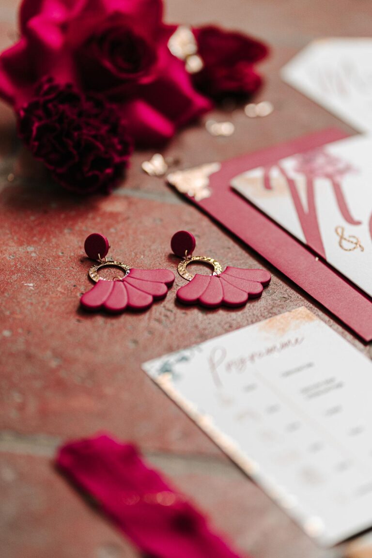 Une papeterie de mariage magenta et dorée posée sur une table.