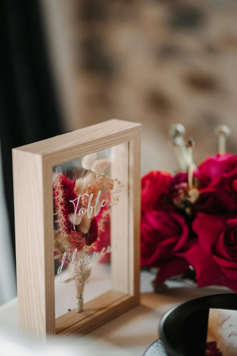 Un cadre en bois avec des roses magenta et un marque-place, une inspiration pour le mariage.