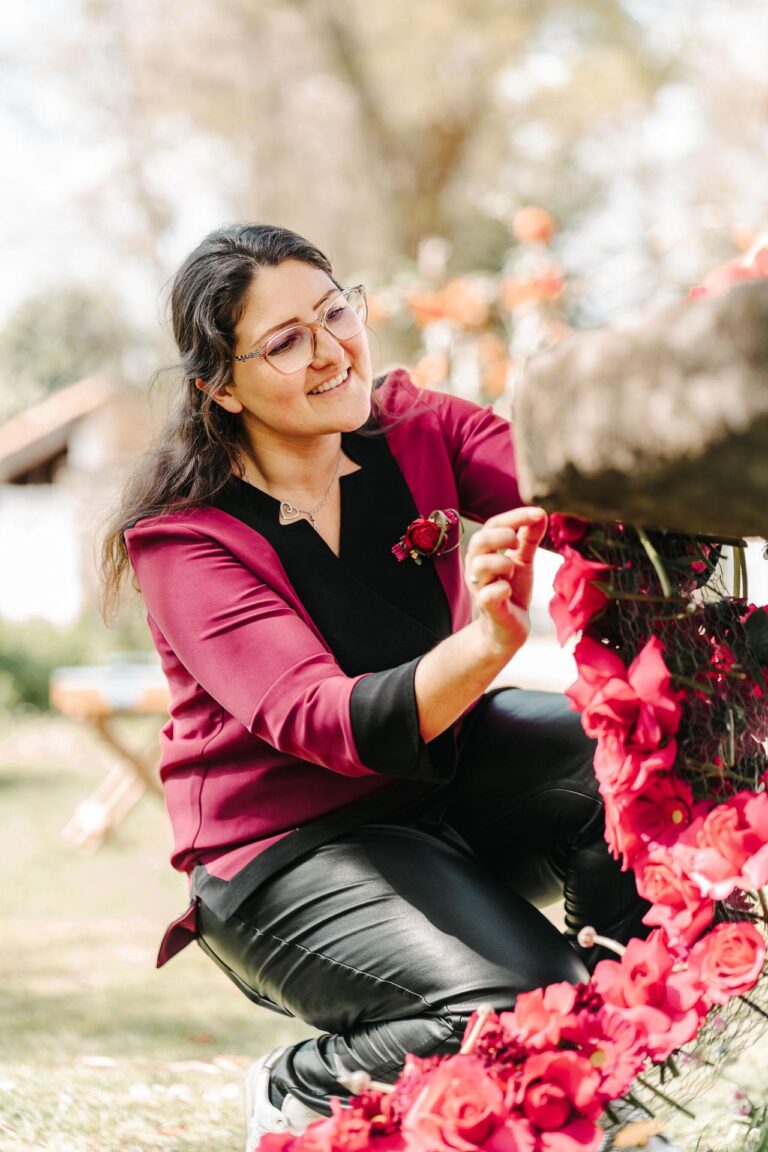 Une femme dépose des fleurs magenta sur un banc.