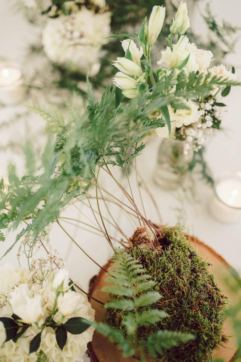 Une table avec des fougères et des fleurs au mariage domaine Petiosse.