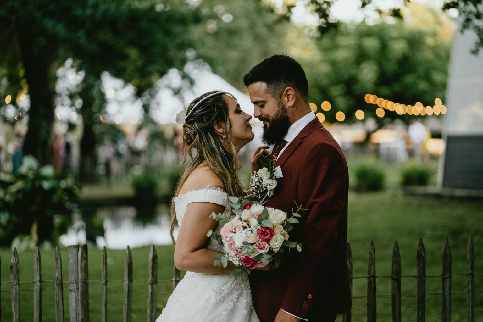 Des mariés s'enlaçant devant une clôture au mariage domaine Petiosse.