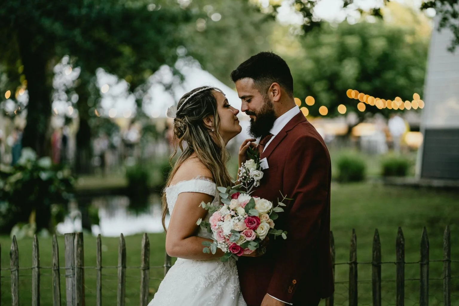 Des mariés s'enlaçant devant une clôture au mariage domaine Petiosse.