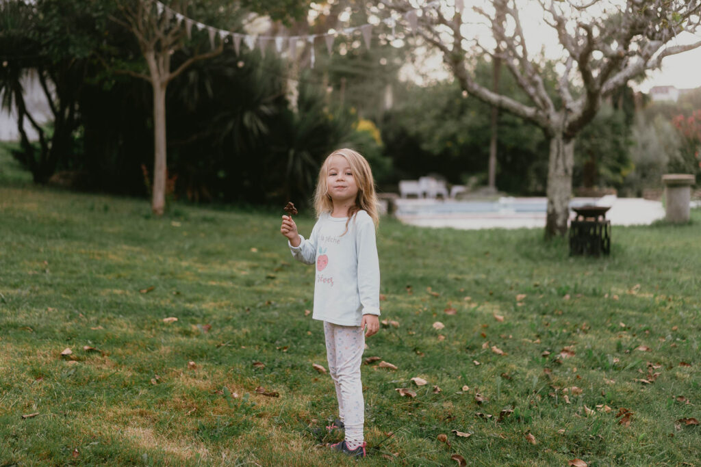 Une petite fille debout dans une cour herbeuse des Pyrénées-Atlantiques.