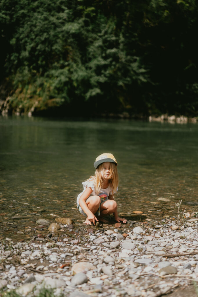 Une petite fille au chapeau jouant dans la rivière dans les Pyrénées-Atlantiques.