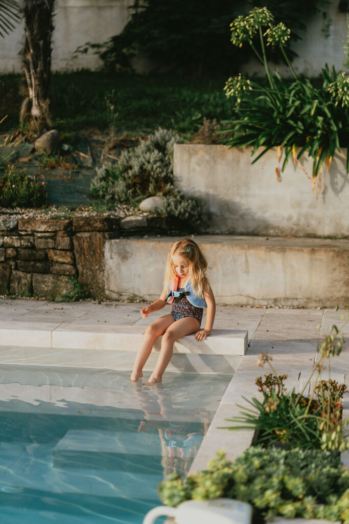 Une petite fille assise au bord d'une piscine dans les Pyrénées-Atlantiques.