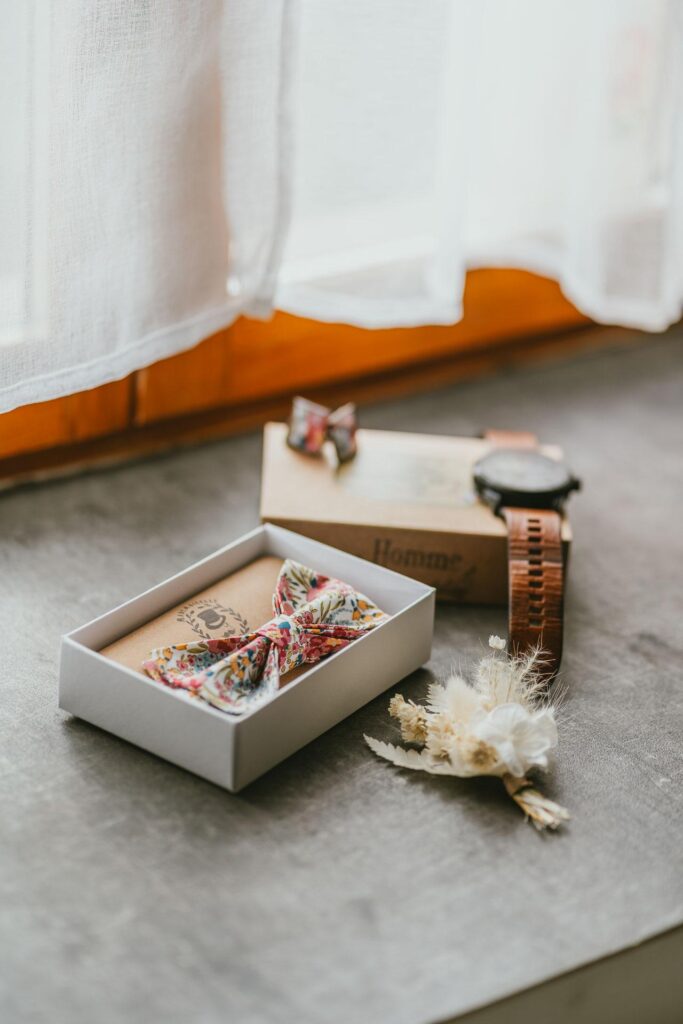 Une boîte avec une montre de mariage et une fleur sur le rebord de la fenêtre.