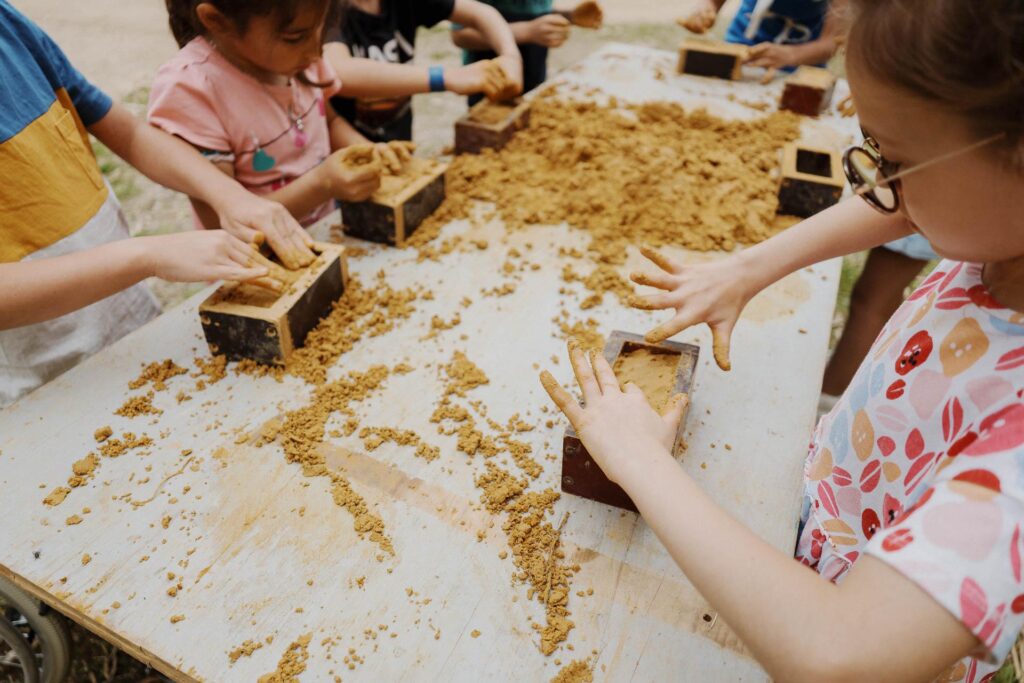 Un groupe d'enfants participant à une activité, jouant avec du sable sur une table.