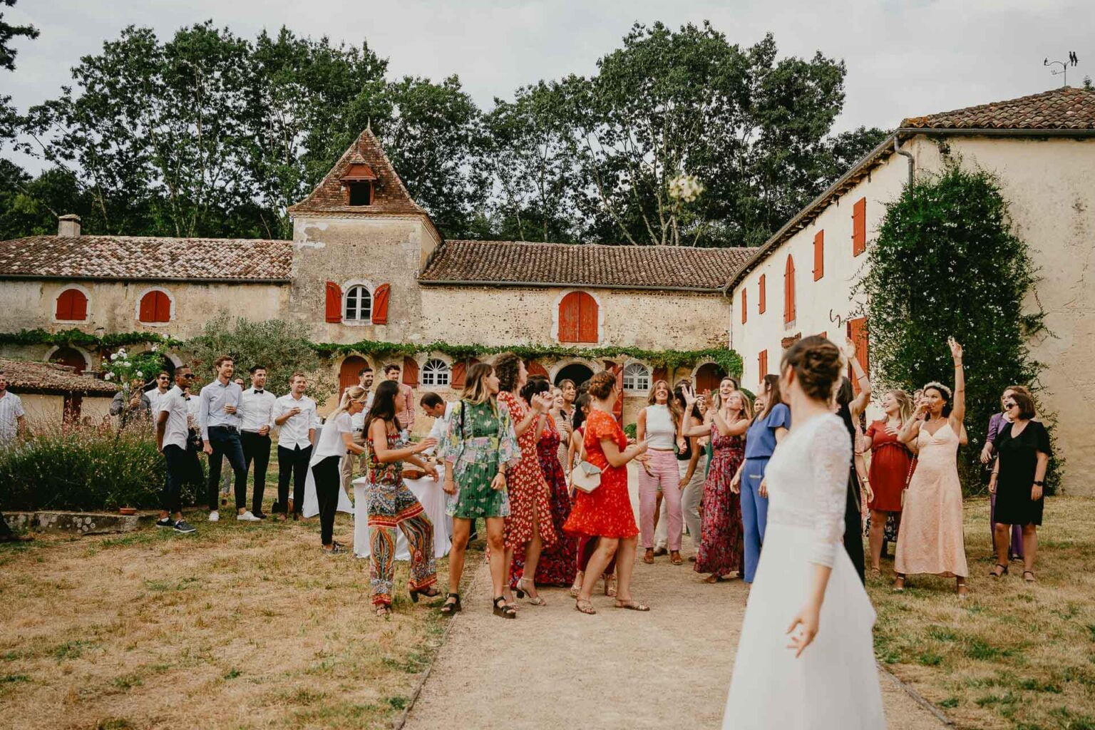 Un groupe de mariés debout devant une maison, rayonnant d’amour.