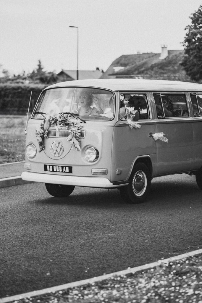 Une photo en noir et blanc d’un mariage hippie dans un bus VW.