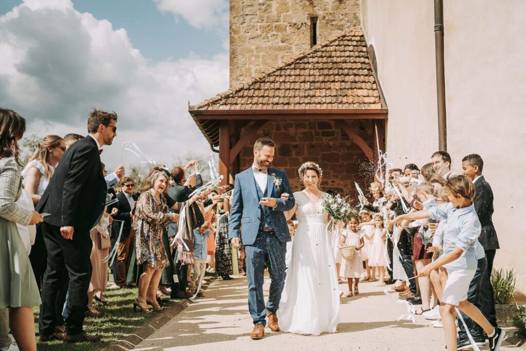 Des mariés marchant dans l’allée d’une église, un moment parfait à capturer pour ceux qui se demandent comment trouver leur photographe de mariage.