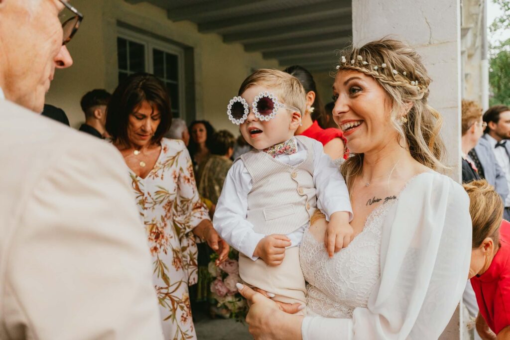 Une femme avec un bébé portant des lunettes de soleil lors d'un mariage hippie.