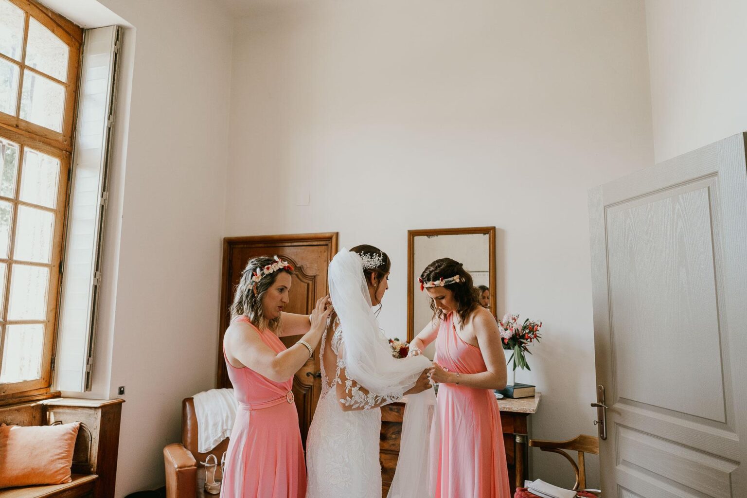 Deux demoiselles d'honneur s'entraident avec leurs robes de mariée lors d'un mariage à Castex d'Armagnac.