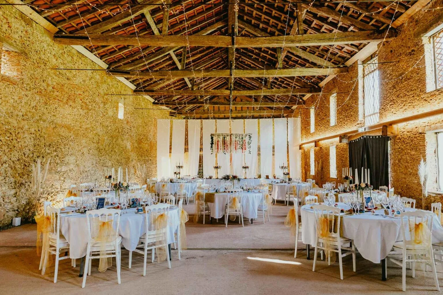 Une réception de mariage Mariage Castex d'Armagnac dans une grange avec tables et chaises.