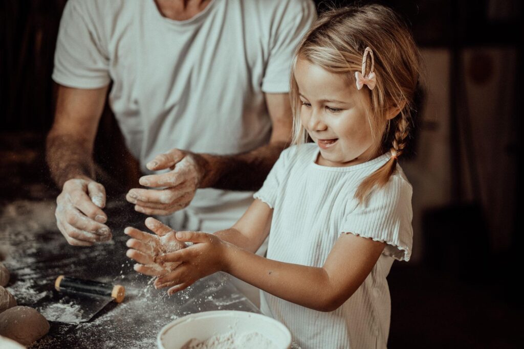 Une petite fille et son père mélangent de la farine dans un bol lors d'une activité dans les Landes.