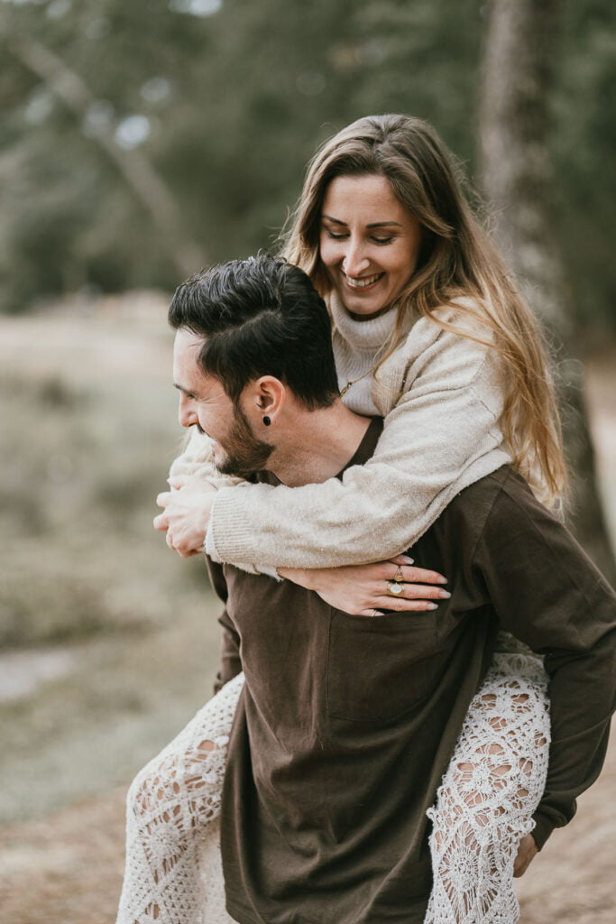 Un photographe capture un homme portant une femme dans les bois lors d'une séance de fiançailles.