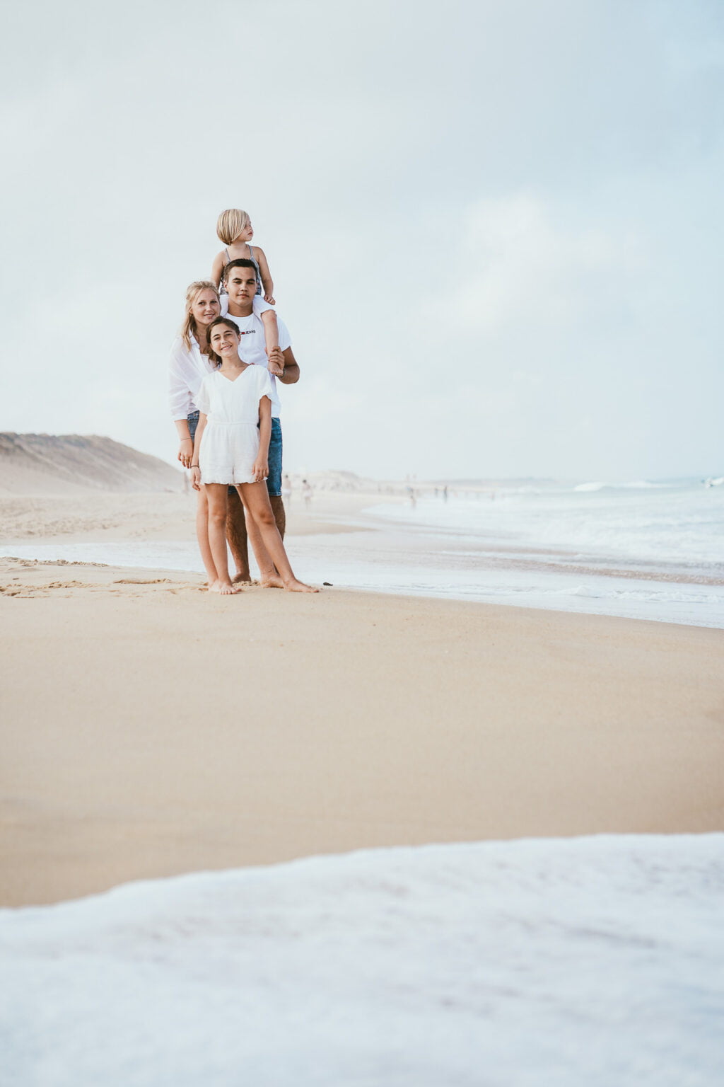 Papa portant sa fille sur ses épaules en bord de mer.