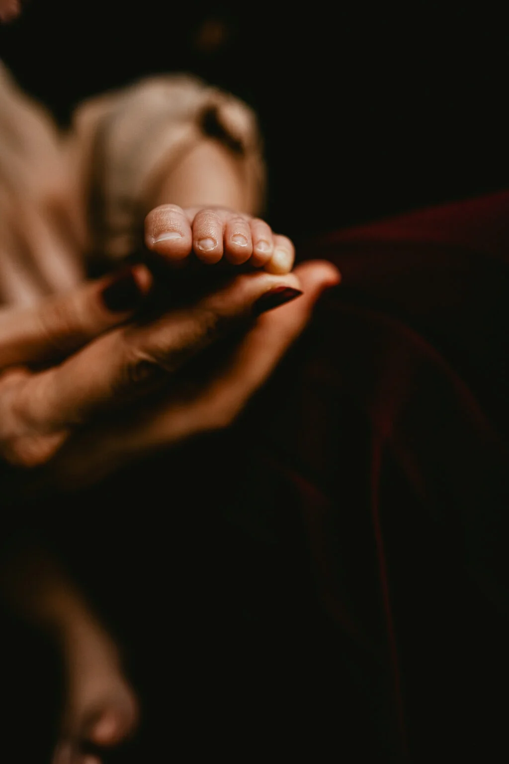 La main d'une femme tenant le pied d'un bébé.