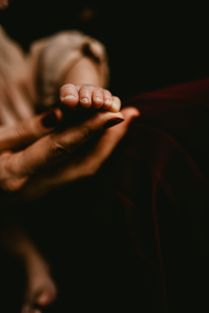 La main d'une femme tenant le pied d'un bébé.