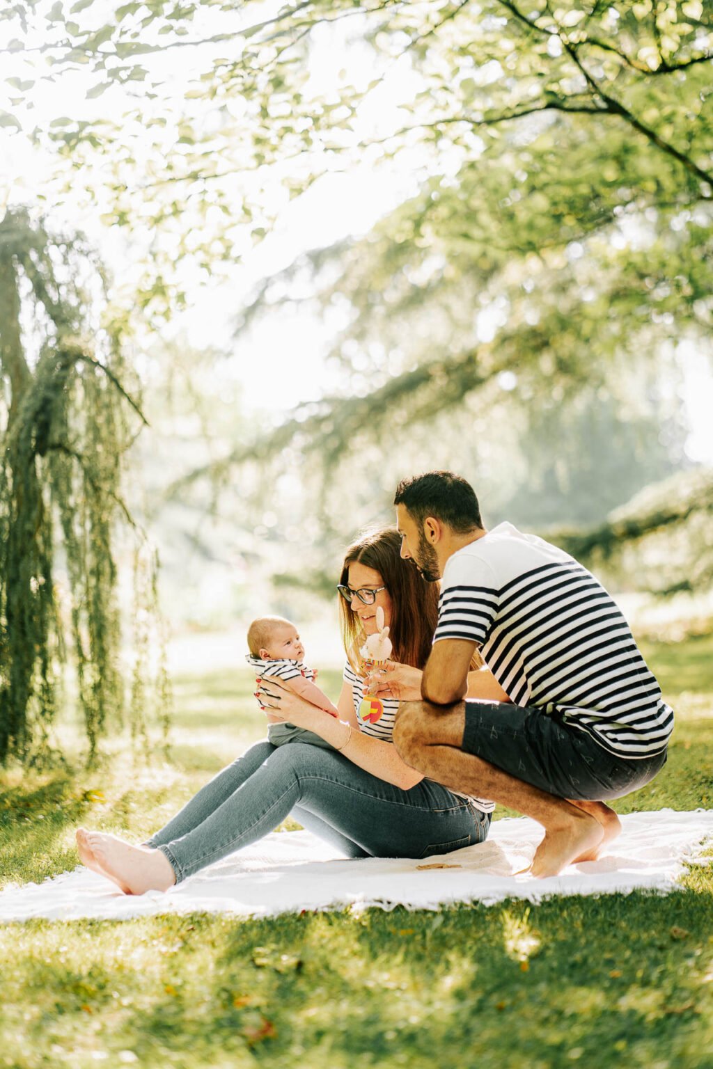 Une famille assise sur une couverture dans un parc.