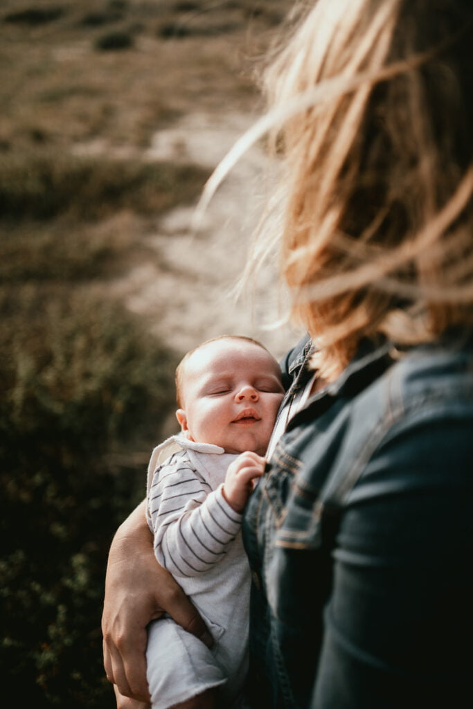 Un nouveau née est photographié dans les bras de sa maman, dans la nature.
