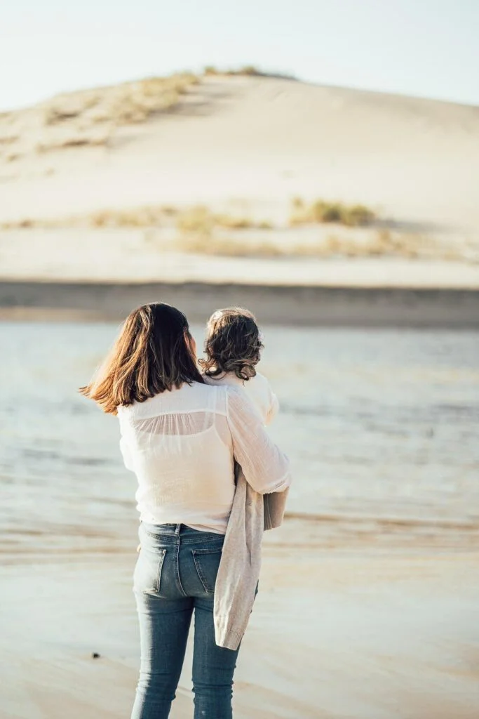 Une femme tenant un enfant sur une photo de séance sur la plage des Landes.