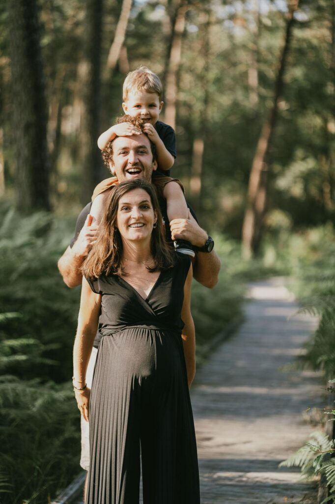 Une femme enceinte et son fils debout dans les Landes pour une séance photo.