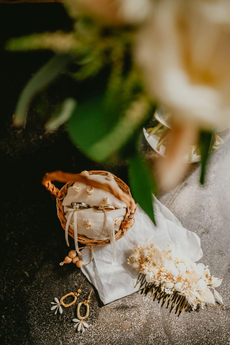 flatlay des accessoires de la mariée avec alliances, bijoux, fleurs et peigne.
