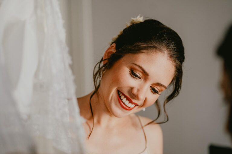 Une mariée sourit en enfilant sa robe de mariée.