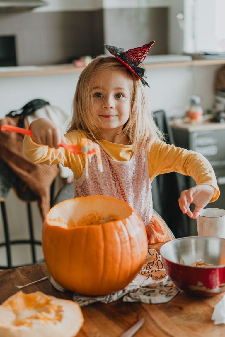 Une petite fille vide une citrouille pour Halloween