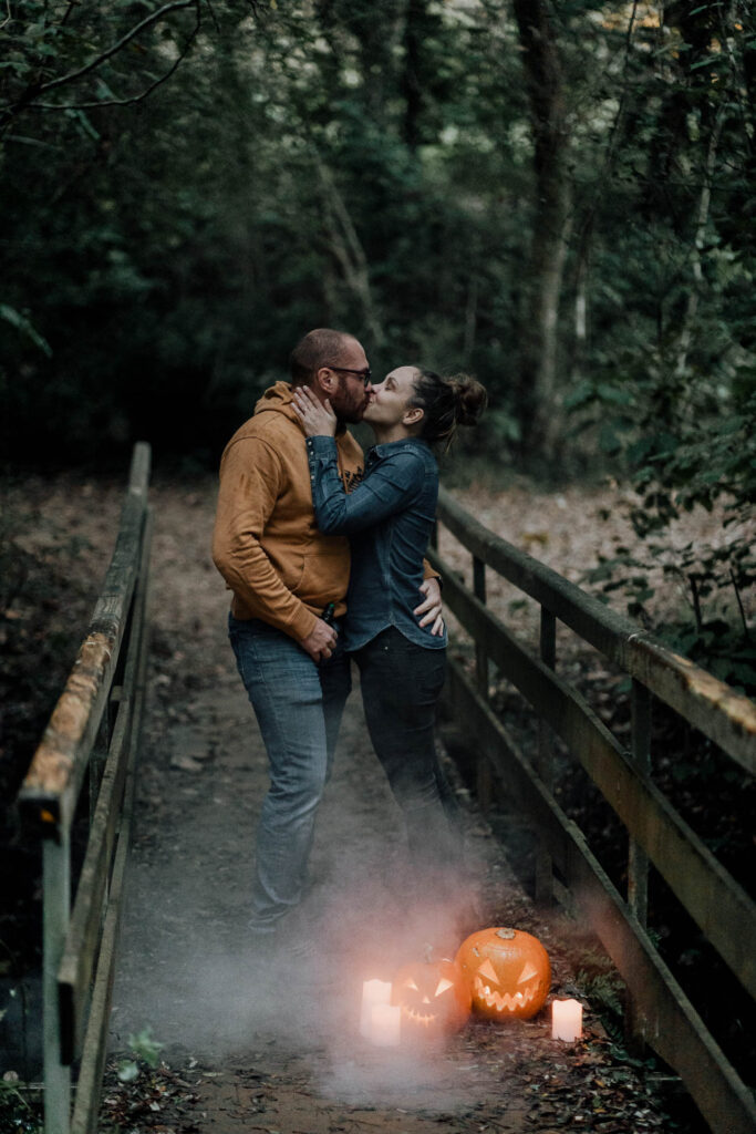 Un couple s'embrasse sur un pont dans la forêt de Dax, des citrouilles d'Halloween a leurs pieds.