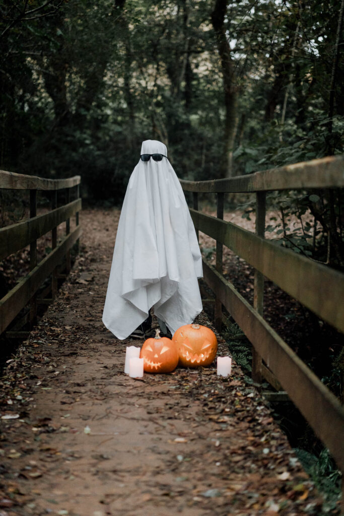 Un enfant a un drap blanc et des lunettes noires et il ressemble à un fantome.