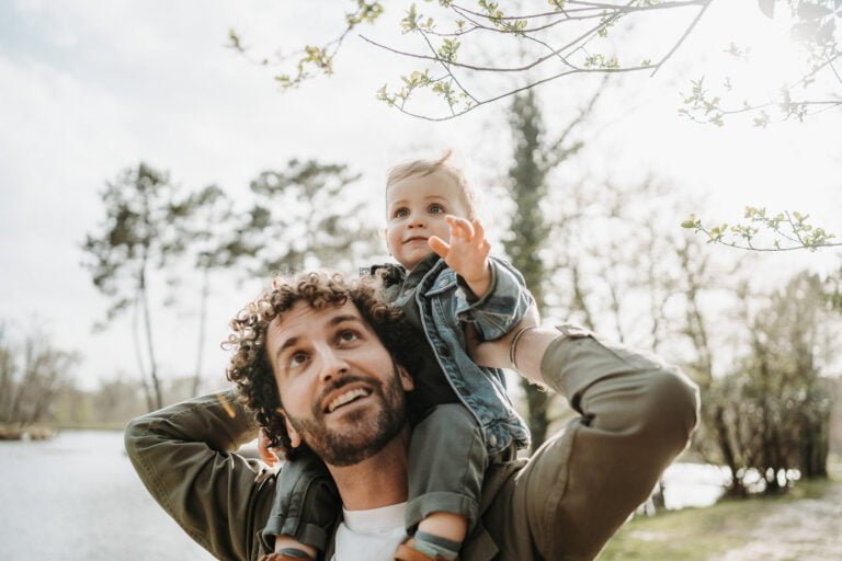 Un homme tenant un bébé dans ses bras dans un parc.